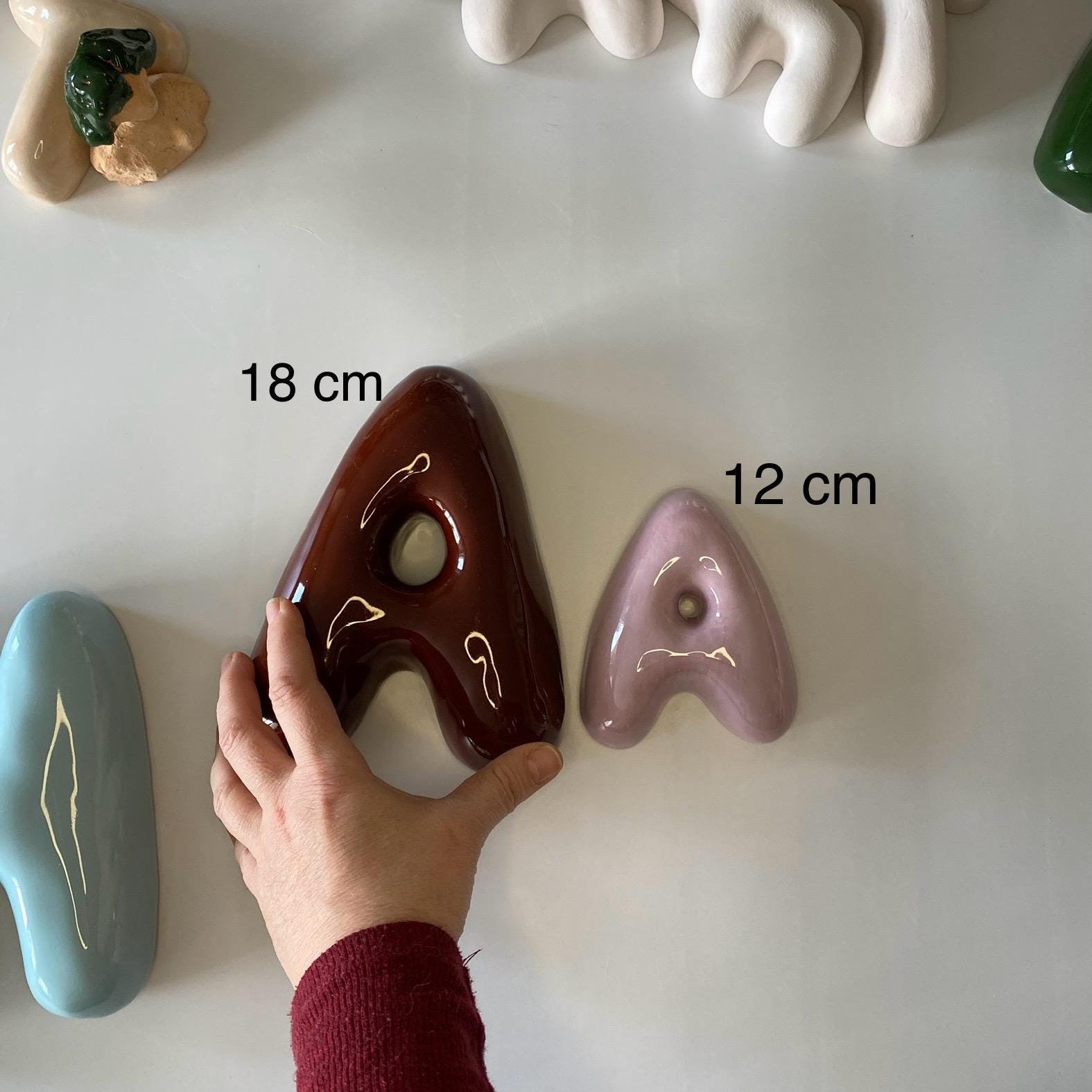 Assorted ceramic letter-shaped objects with measurements on a white surface
